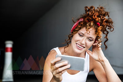 Smiling redheaded woman holding cell phone