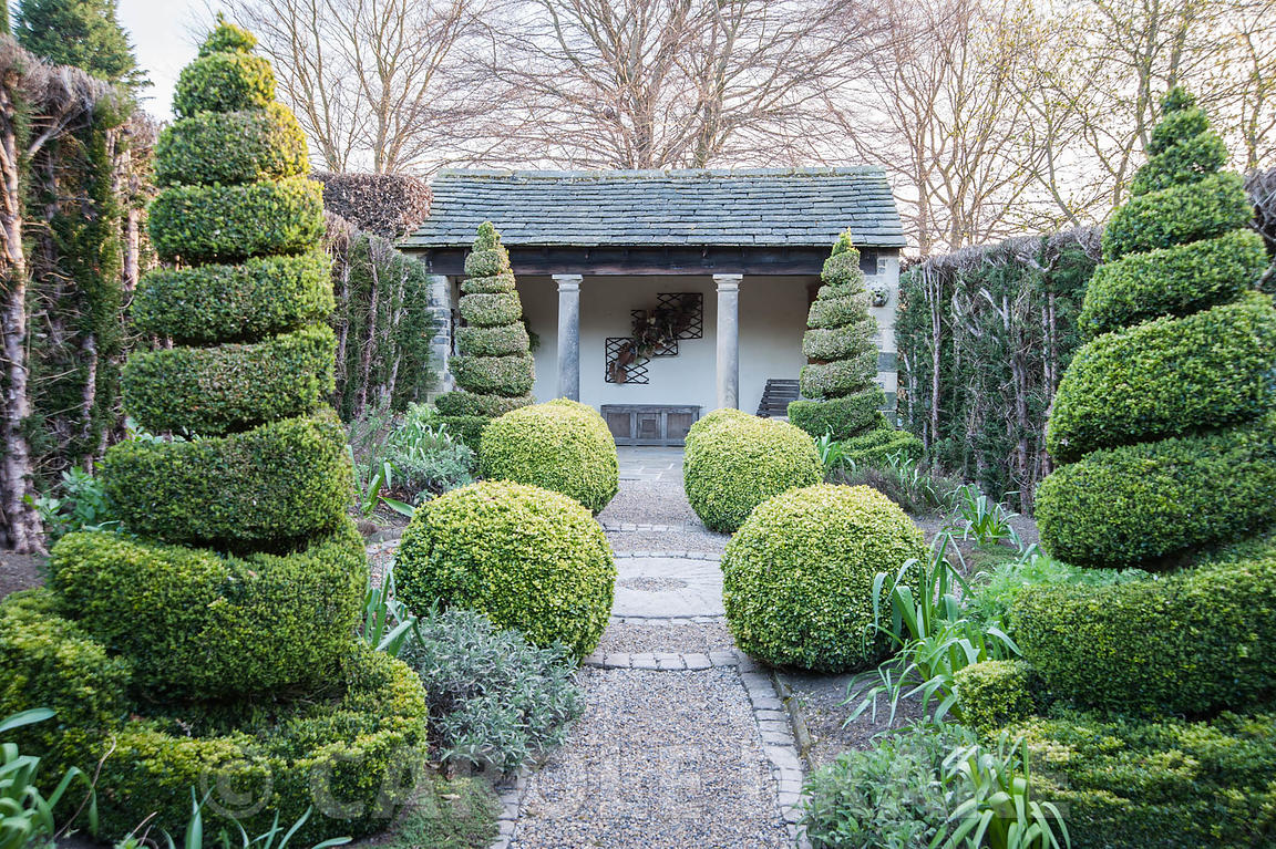 The Herb Garden with topiary box and yew and a summer house at the end. York Gate Garden, Adel, Leeds, Yorkshire