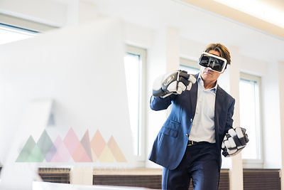 Businessman wearing VR glasses and ice hockey gloves in office