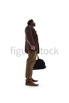 A Figurestock image of a man in a leather Jacket, standing, holding a black bag and looking up – shot from low level.