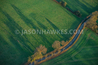 Aerial view of country lane winding through fields, England, UK.