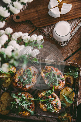 Baked stuffed potatoes with cheese, vegetables, sour cream and rucola on wooden table. Top view