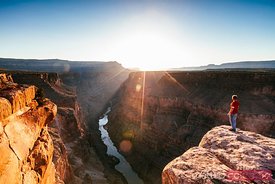 Tourist on the edge of the Grand Canyon at sunrise, USA