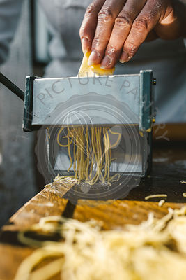 A WOMAN MAKING HOMEMADE PASTA IN THE TRADITIONAL WAY