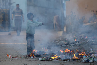 A boy warms himself by a fire in the streets of Pushkar, Rajasthan, India