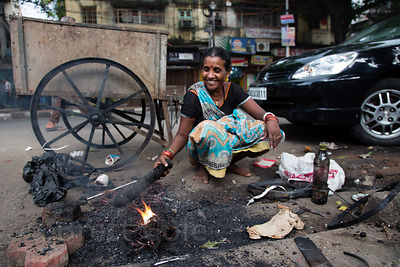 A trash worker burns copper wires to get the plastic casings off so the copper can be recycled, Taltala, Kolkata, India