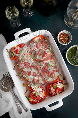 Black Rice Caprese Stuffed Roasted Red Peppers served with a fresh Basil Oil and white wine. Photographed from top view on a dark blue background.