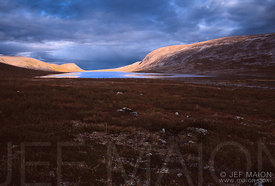 Ombre et lumière sur lac, collines, et végétation de toundra