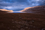 Ombre et lumière sur lac, collines, et végétation de toundra