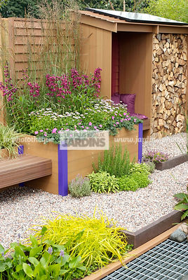 Abri de jardin dans un jardinet urbain. Jardinière en plastique recyclé. Carex elata 'Aurea', Geranium sanguineum, Parterre en gravillon. Paysagiste : Tim Fowler, TPFS, Angleterre