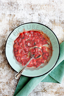 Strawberry Basil Jam served in a enamel bowl. Photographed on a rustic white background.