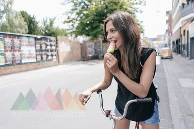 Woman with bicycle eating ice lolly