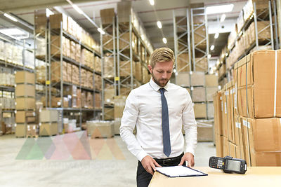 Businessman with clipboard and barcode scanner in warehouse