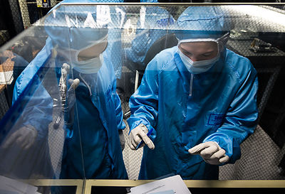 Ingénieurs préparent le montage des éléments du sismomètre ultrasensible SEIS Seismic Experiment for Interior Structures, devant une hotte à flux laminaire d'une salle blanche de l'entreprise Sodern.