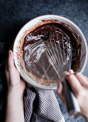 A womans hand whisking chocolate sauce in a bowl