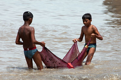 Boys from the Colaba fishing village in Mumbai, India haul in a net full of garbage. The boys bring the net back and dump it in an old wooden boat, then frantically sift through the garbage to yield an average of two or three tiny fish per net.