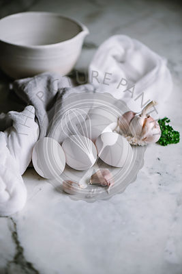 White eggs with garlic cloves on a marble worktop in a kitchen