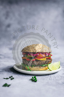 Vegan Mexican black bean and quinoa burger on sesame bun with lime and picked onions