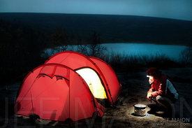 Backpacker cooking by tent by night