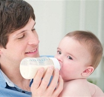 Father feeding baby with milk