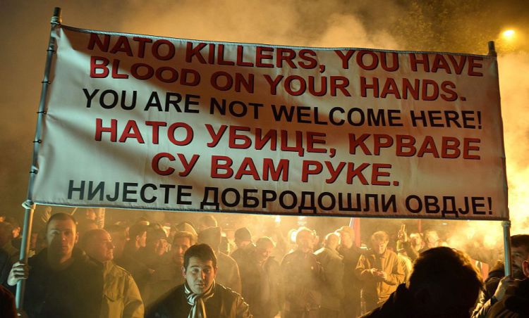 epa05066976 Protesters holds a banner reading 'NATO killers, you have blood on your hands' during a protest in downtown Podgorica, Montenegro, 12 December 2015. NATO Foreign Ministers on 02 December invited Montenegro to become the 29th member and third West Balkan nation to join NATO after Albania and Croatia. Russia should have no say on the country's decisions, top NATO officials and ministers said. EPA/BORIS PEJOVIC