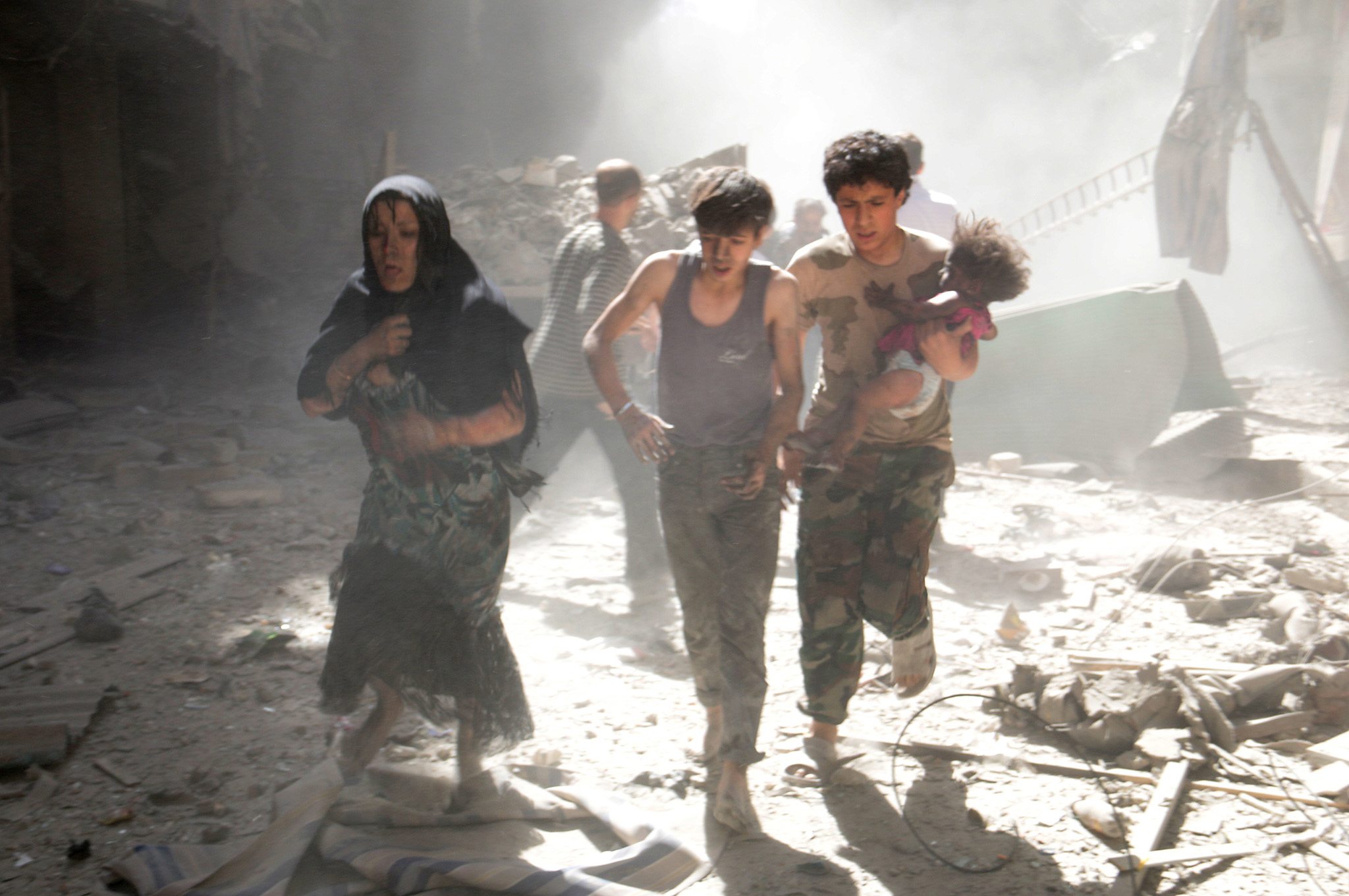 TOPSHOTS A Syrian woman and youths, one of them carrying a wounded baby, flee the site of a reported barrel-bomb attack by Syrian government forces in the northern city of Aleppo on June 26, 2014. Syria's war has killed more than 162,000 people and forced nearly half the population to flee their homes. AFP PHOTO /AMC / ZEIN AL-RIFAIZEIN AL-RIFAI/AFP/Getty Images