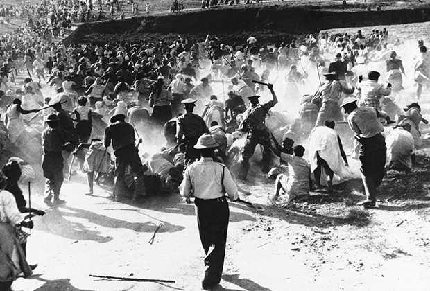 South African police beat African women with clubs in Durban in 1959, when the women raided and set fire to a beer hall in protest against police action against their home brewing activities. South Africa's racial segregation policies still trouble the nation.