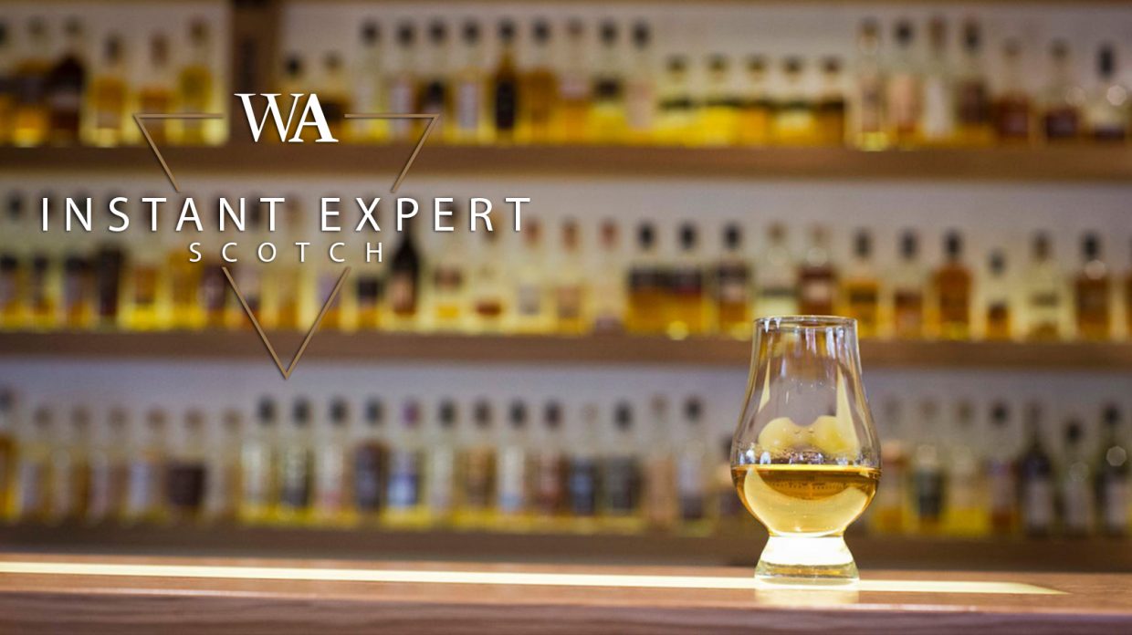 Glencairn glass of scotch whisky in front of a shelf of bottles with the words "Instant Expert Scotch" and Whisky Advocate logo.