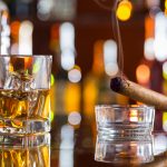 Whiskey drink with smoking cigar on bar