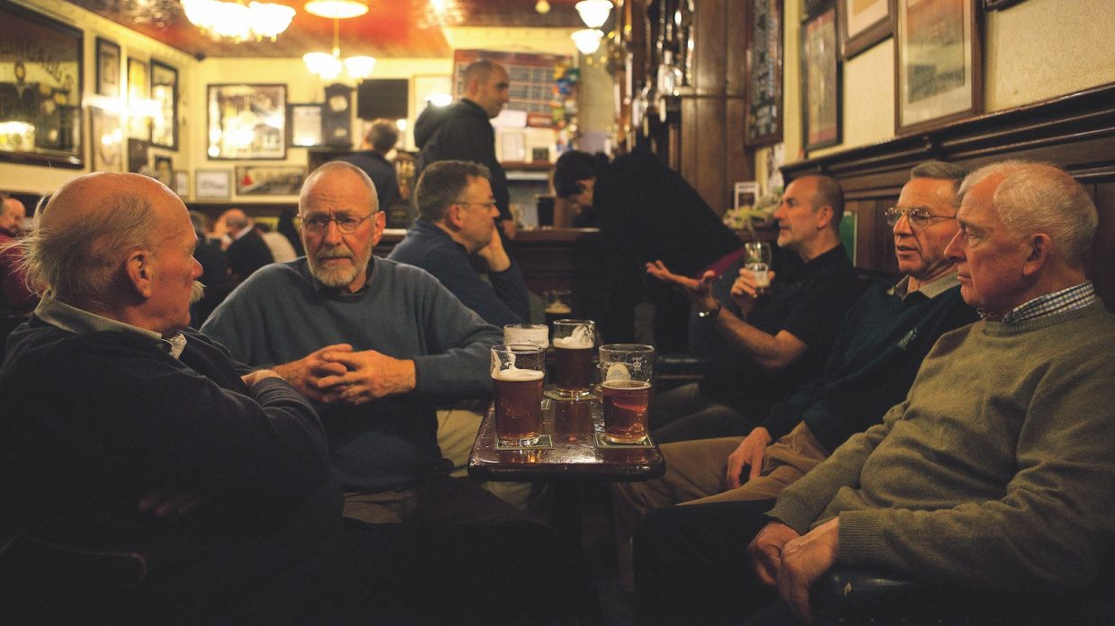 Several men gather to drink beer at the Bow Bar in Edinburgh, Scotland.