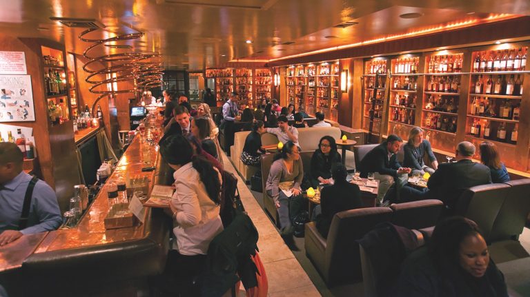A bunch of people gather at the bar and in booths of the Brandy Library.
