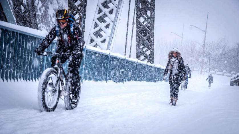 Un cycliste roulant à vélo d’hiver et des marcheurs se côtoient sur la passerelle du pont Alexandra en hiver.