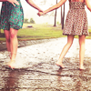 Two girls in dresses walking hand in hand.