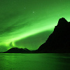 a green aurora arching over a dark mountain.