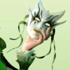 A mask held by a hand with a green ruffled sleeve.