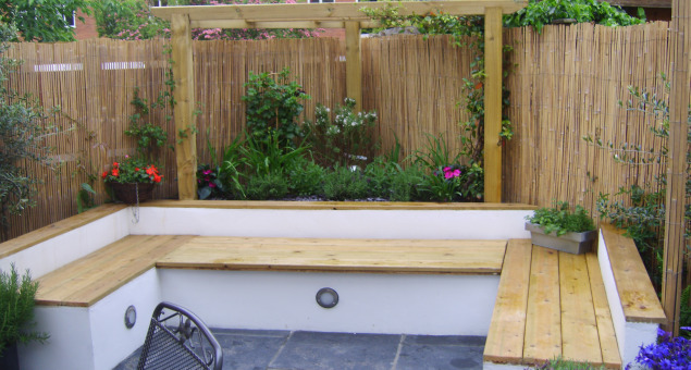 Rendered raised beds increase the feeling of intimacy in this area and also in the rear corner, where an arbour shades a built-in seat with storage underneath.