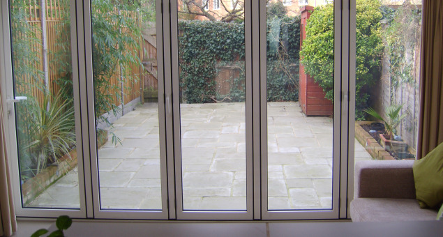 This is the original outlook through the bi-fold doors looking out onto a rather uninspiring paved area with a small shed and little else. 
