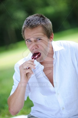 Young man licking ice lolly picture