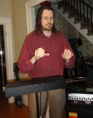 Caption: Kevin Colusa playing the theremin in his living room.