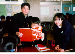 Caption: Students in Fukushima, seen here studying American junior high school yearbooks.