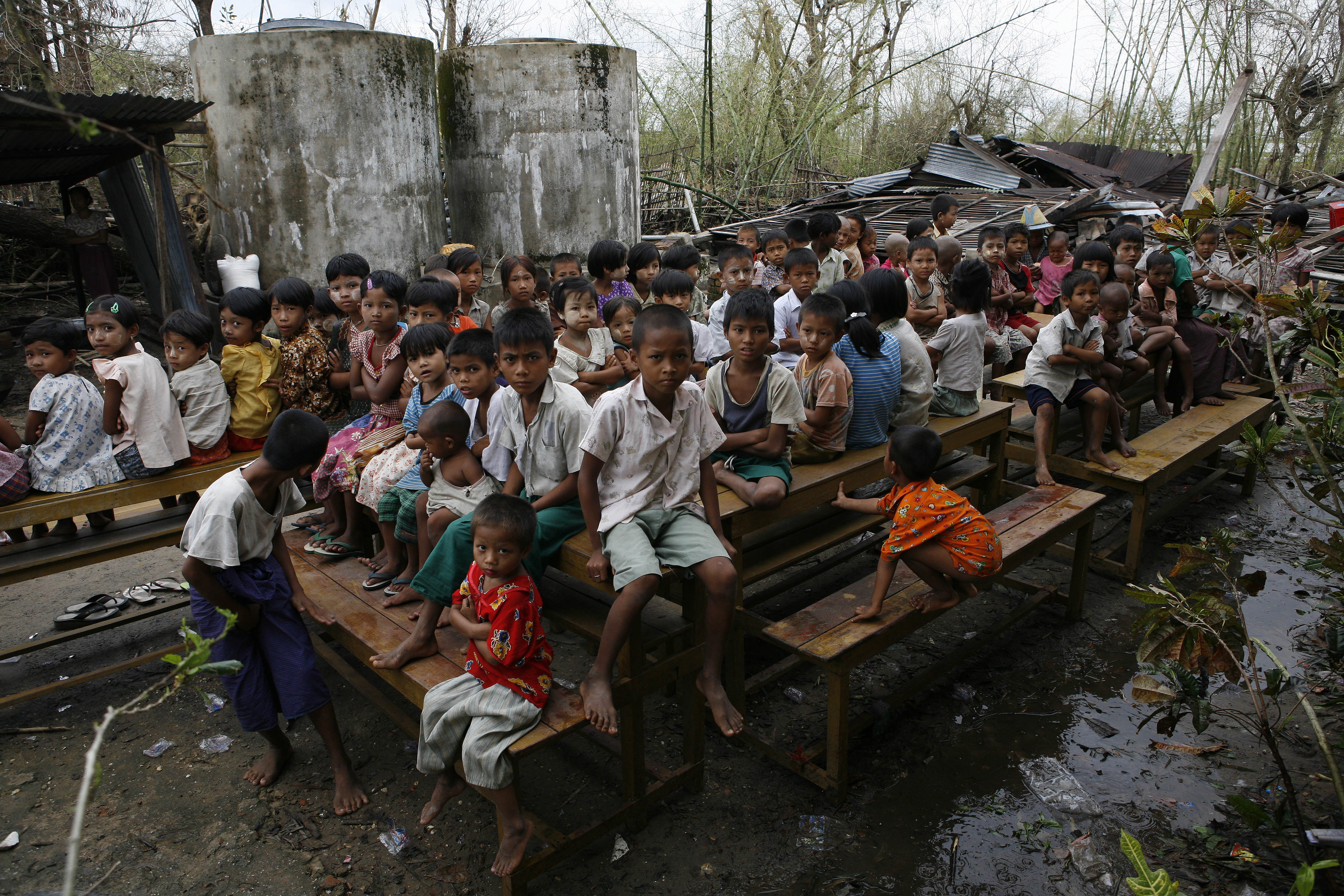 Caption: Children congregate outside a school that serves as a temporary camp for those displaced by the cyclone, near the town of Kundangon in the south-western Irrawaddy Division. The children lost their homes, and much of the school was destroyed., Credit: UNICEF/NYHQ2008-0340/Dean