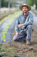 Caption: Jason Brashears and his young okra plants, Credit: Guy Hand