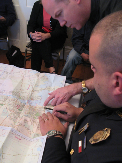 Caption: Fr. Wilson & Office Corrolla examine a map of the city, Credit: Will Coley
