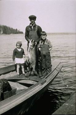 Caption: Early North Shore commercial fisherman with children and lake trout., Credit: Photo courtesy of the North Shore Commercial Fishing Museum