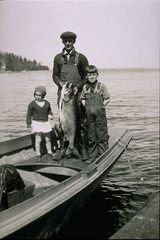 Caption: Early North Shore commercial fisherman with children and lake trout., Credit: Photo courtesy of the North Shore Commercial Fishing Museum