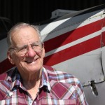 Caption: Harold Blackledge, a 79-year-old agricultural pilot, stands in front of his 1975 Piper Pawnee Brave in one of his hangars at the Watonga Regional Airport. The drought — the worst he’s seen — has dried up aerial spraying work in Oklahoma, he says., Credit: Joe Wertz