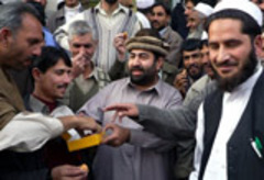 Caption: Local residents share sweets after the government decision to implement Islamic Law in Pakistan's Swat Valley., Credit: Associated Press