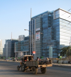 Caption: Tractor travels past modern building in Gurgoan, India, Credit: Kristin McHugh for the Stanley Foundation