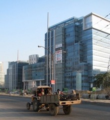 Caption: Tractor travels past modern building in Gurgoan, India, Credit: Kristin McHugh for the Stanley Foundation