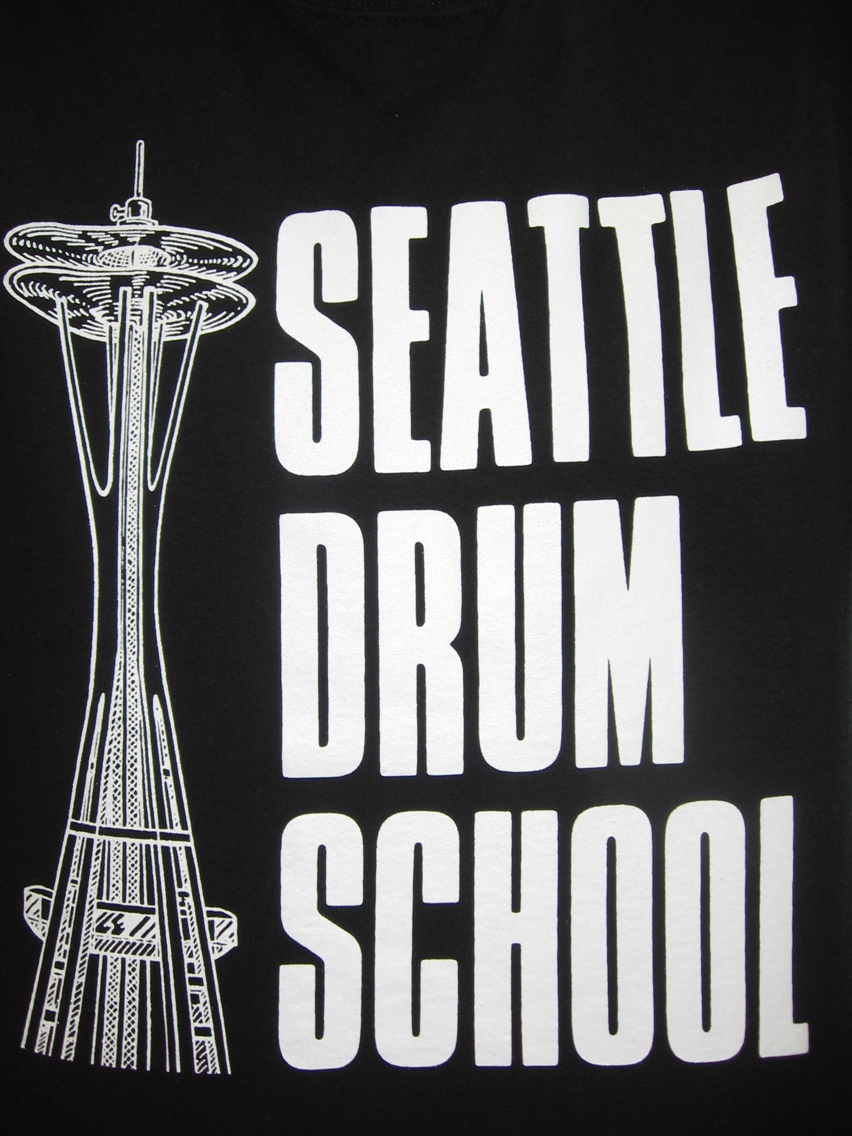 Caption: A t-shirt showing the logo of the Seattle Drum School. Artur Sapek hosted today's podcast live from the school to find out how musicians are being impacted by the recession., Credit: Artur Sapek
